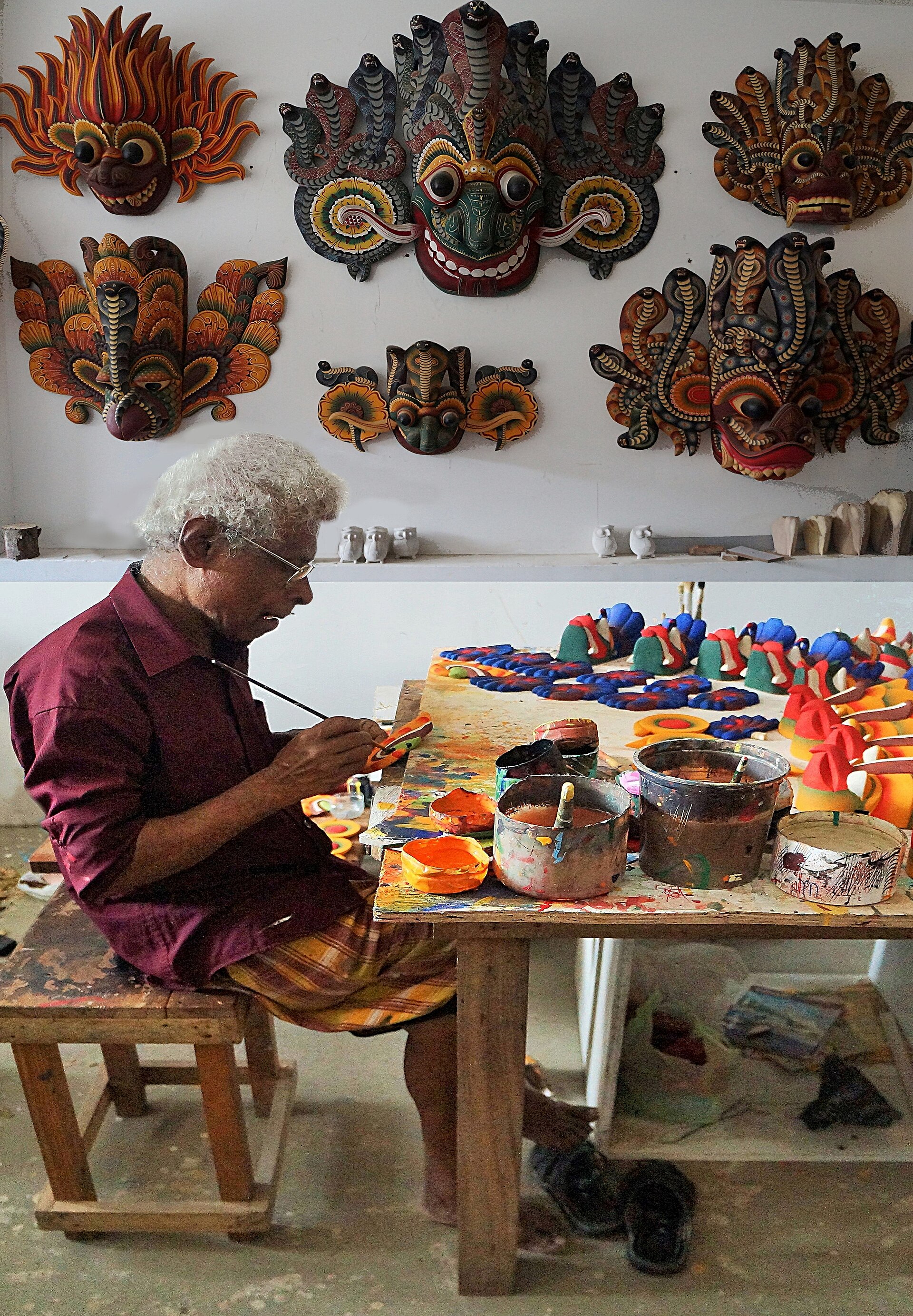 A craftsman painting a carved wooden mask by hand at a wood carving centre in Polonnaruwa.