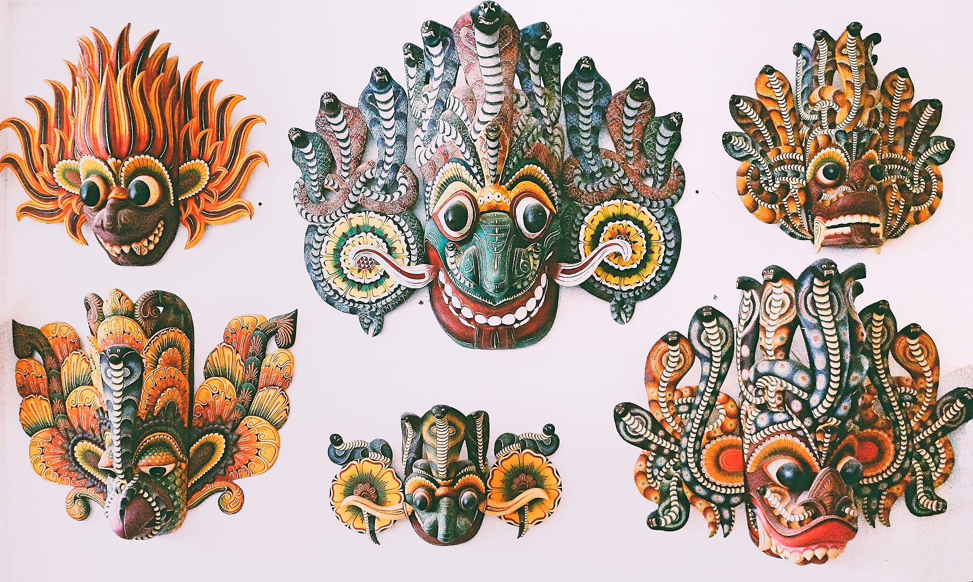 Rows of brightly painted traditional Sri Lankan masks displayed on a workshop wall.